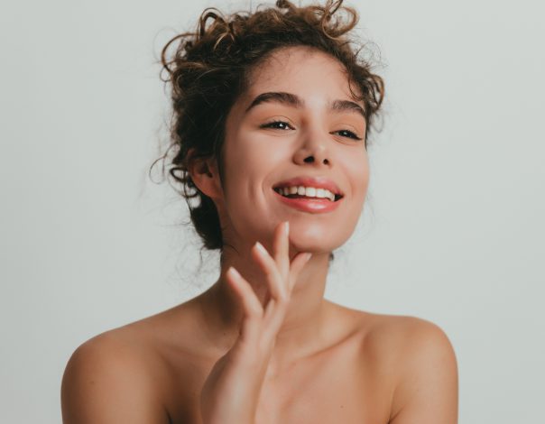 Sculptra treatment woman with glowing, smooth skin smiles with curly hair