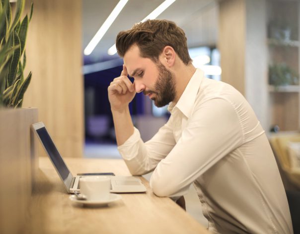 Man with migraine sitting and looking at a computer
